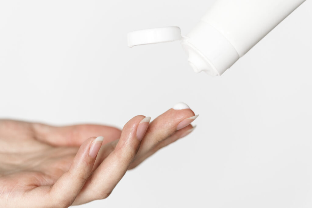 Woman's hand getting topical cream from bottle