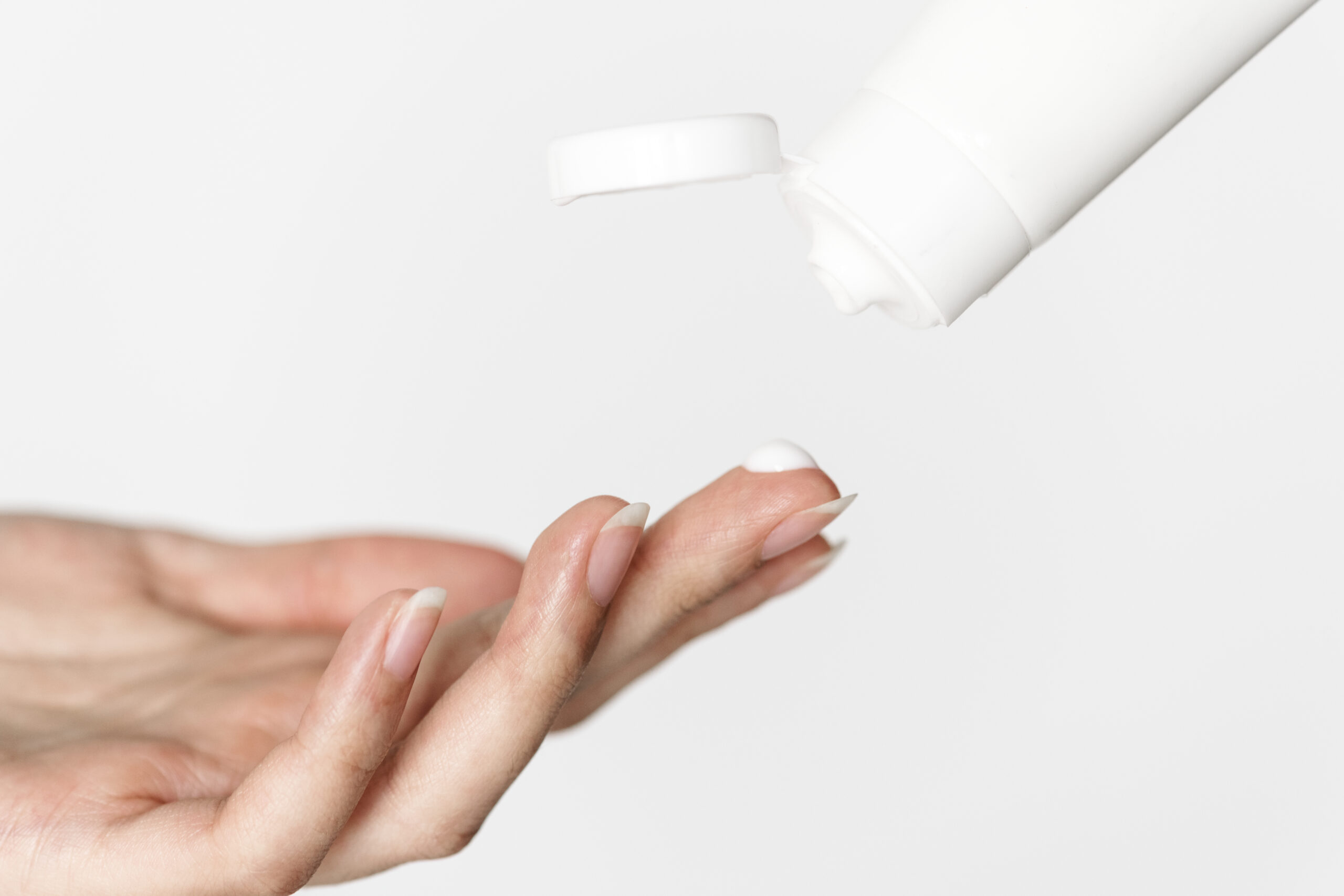 Woman's hand getting topical cream from bottle