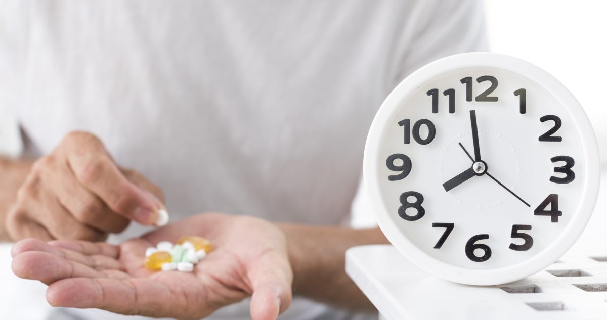Man taking medication with clock telling time