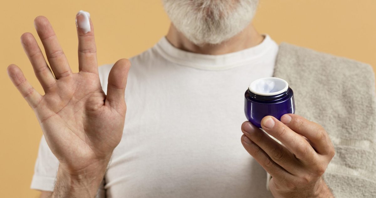 Front view of senior man with beard holding moisturizer