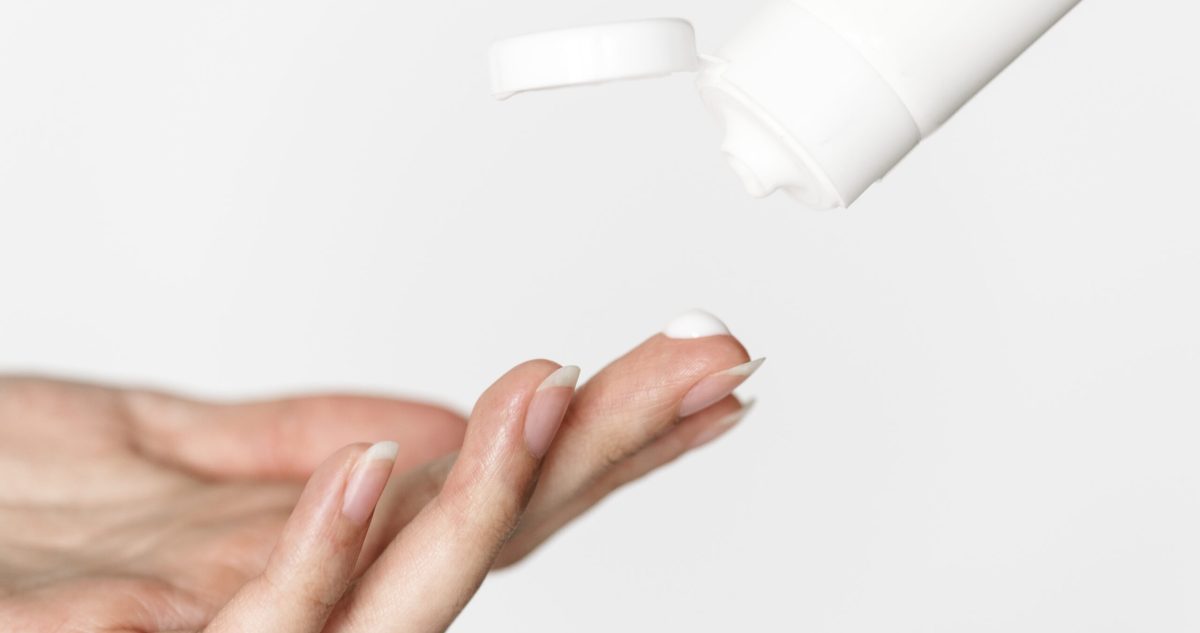 Woman's hand getting topical cream from bottle